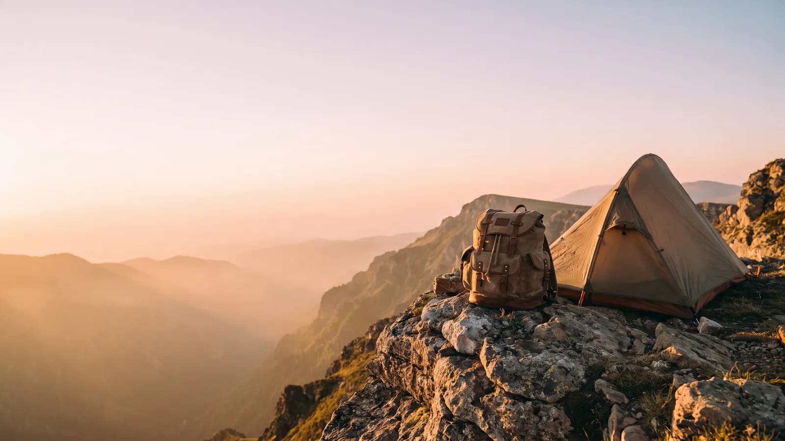 La misma cresta de montaña al amanecer tal como la pintó el modelo de imagen, antes de cualquier palabra: la carpa y la mochila a la derecha, cielo claro y despejado a la izquierda